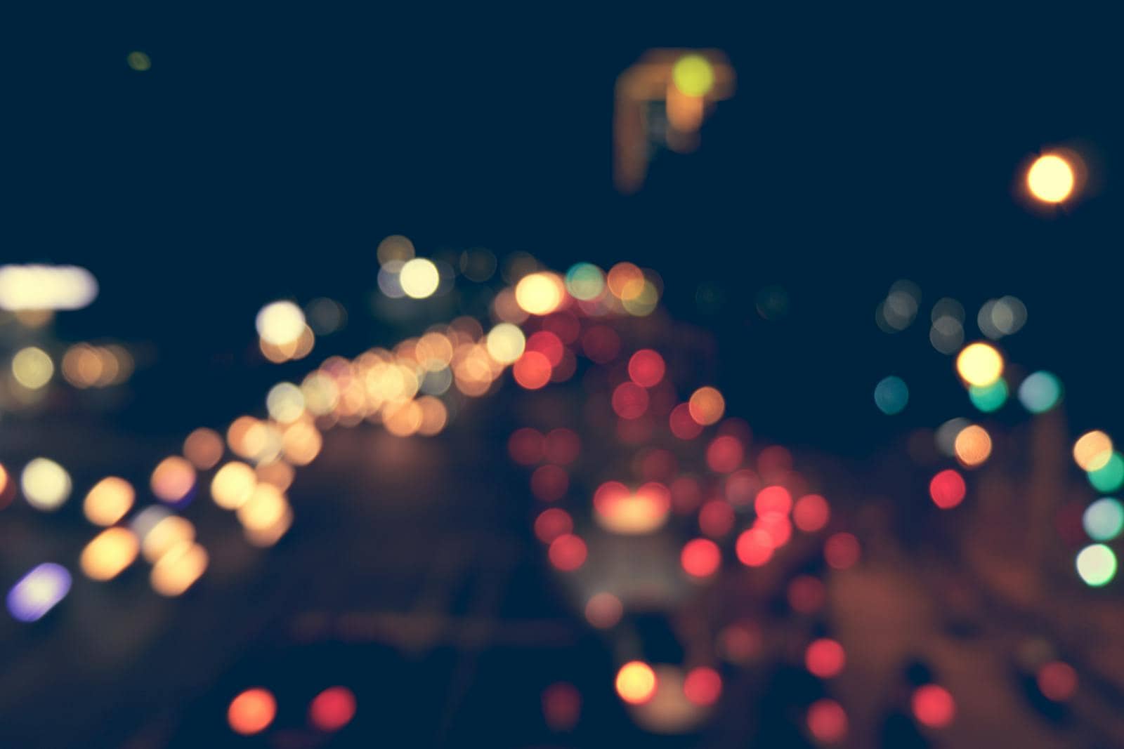 Blurred city traffic at night with colorful bokeh lights creating an abstract visual effect.